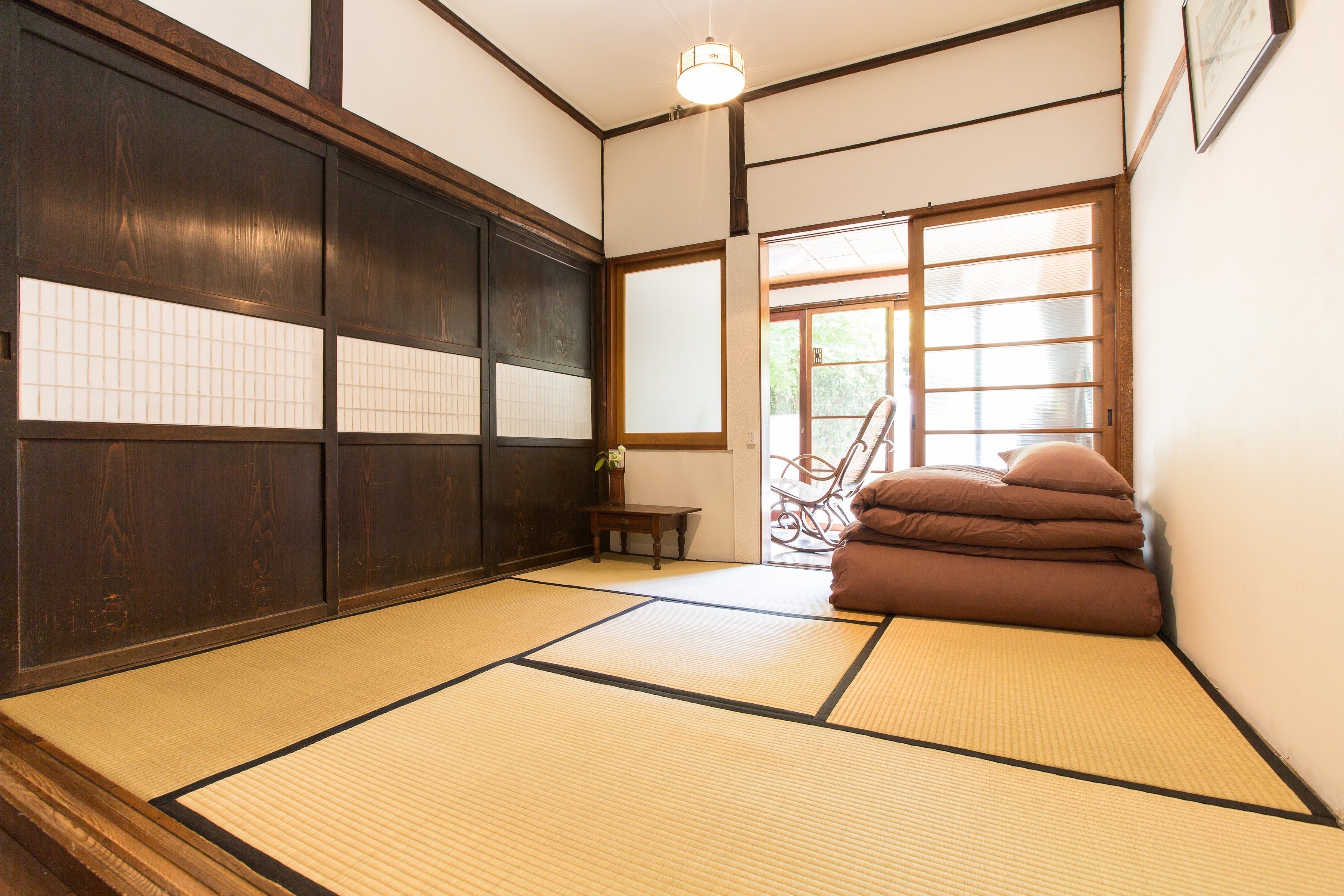 A tatami mat room with a sliding door, a small table, and a chair.