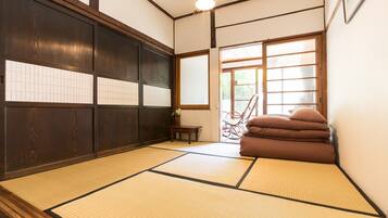 A tatami mat room with a sliding door, a small table, and a chair.
