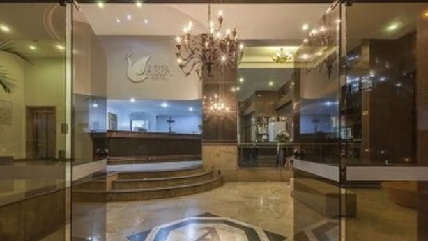 A hotel lobby with a reception desk, a chandelier, and a large logo on the floor. - Hotel Abba (Betim)