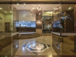 A hotel lobby with a reception desk, a chandelier, and a large logo on the floor. - Hotel Abba (Betim)
