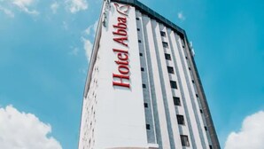 A tall hotel building with the name "Hotel Abha" prominently displayed on its facade. - Hotel Abba (Betim)
