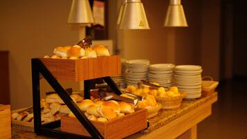 Een buffetopstelling met broodjes en manden vol fruit.