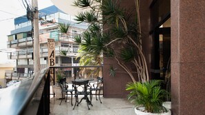 A hotel entrance with a signboard, a balcony with a table and chairs, and potted plants. - Hotel Abba (Betim)