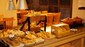 A buffet counter with various baked goods and bread baskets. - Hotel Abba (Betim)