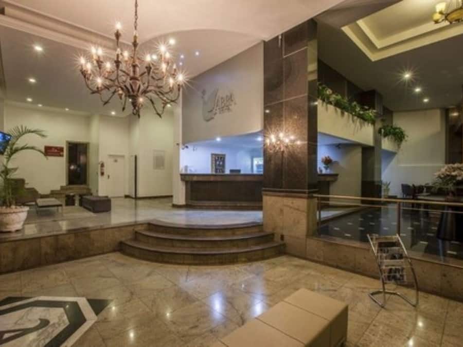 A lobby with a chandelier, a reception desk, and a staircase leading to upper floors.