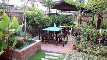 A patio with a table and chairs, surrounded by potted plants and a small water feature.