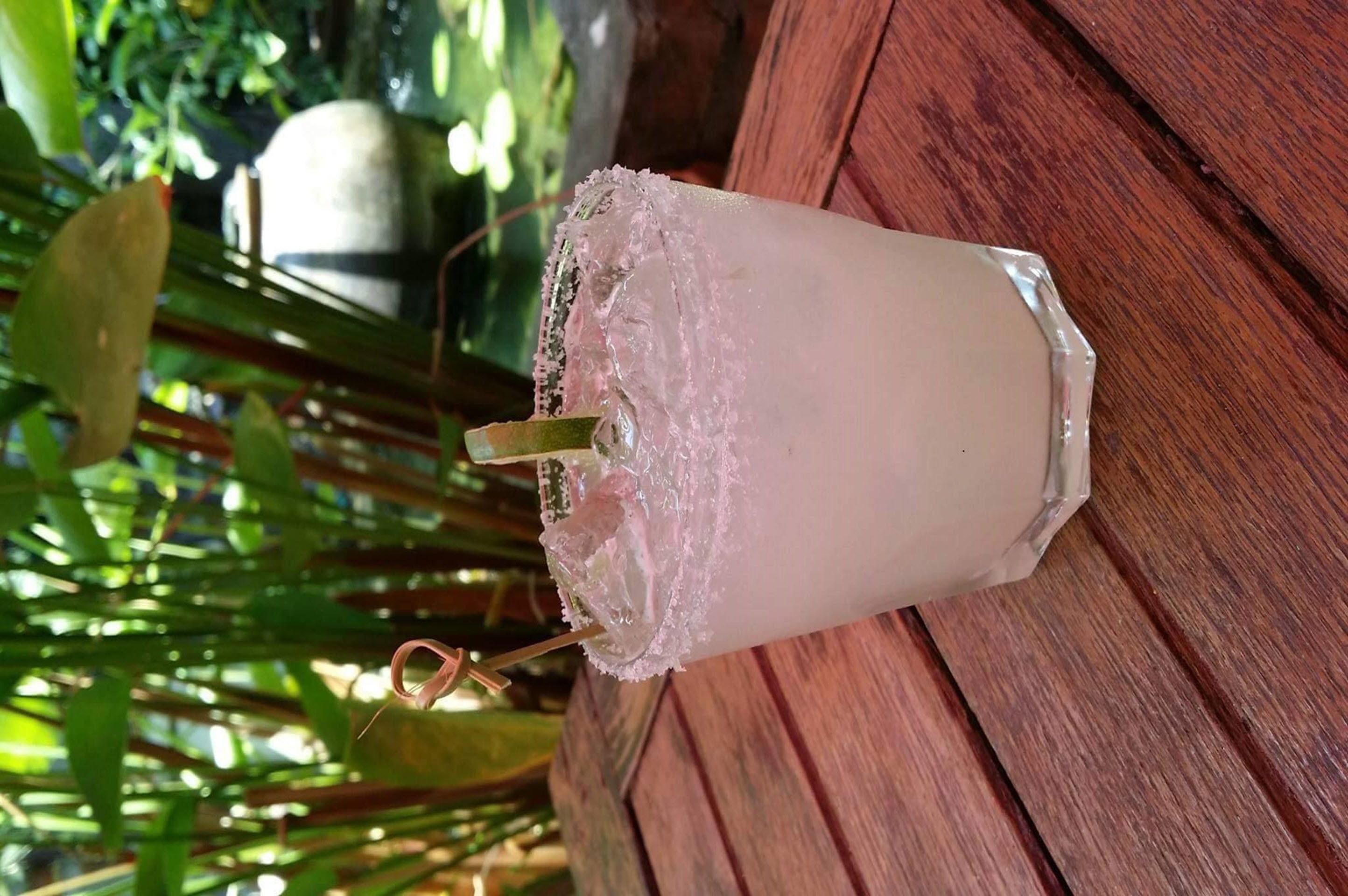 Un verre contenant une boisson glacée, une paille et une garniture décorative, le tout posé sur une surface en bois.