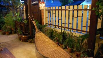 A hammock in a garden area with potted plants and a wooden fence.