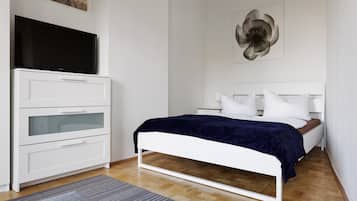 A bedroom with a bed, a dresser, a flat-screen TV, and a wall art piece.