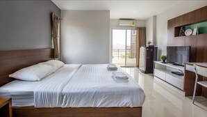 A modern hotel room with a large bed, a TV, a desk, and a balcony with a view. - Central place serviced apartment 1 (Chonburi)
