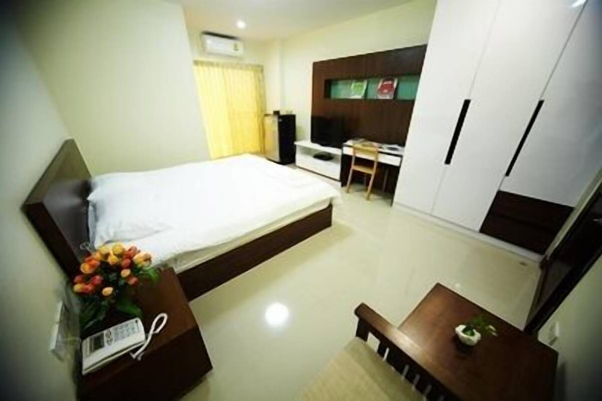 Una habitación de hotel con cama, escritorio, silla, mesita y armario.