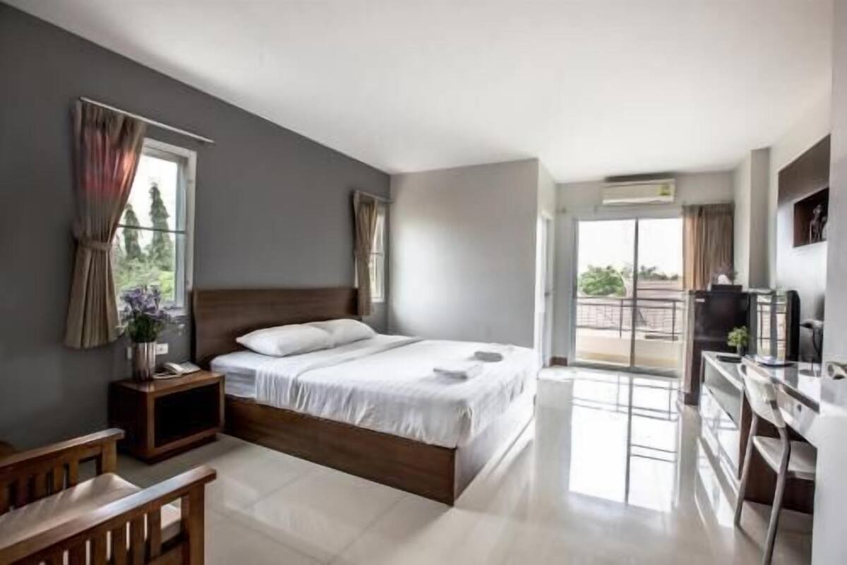 Un dormitorio moderno con una cama grande, un escritorio y un balcón.