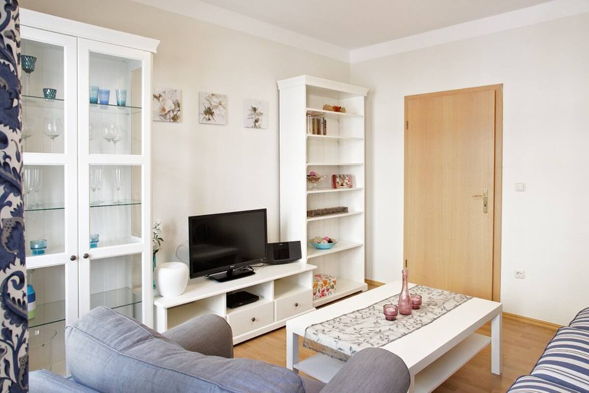 Un salon avec un canapé, un téléviseur, des étagères blanches et une porte en bois.