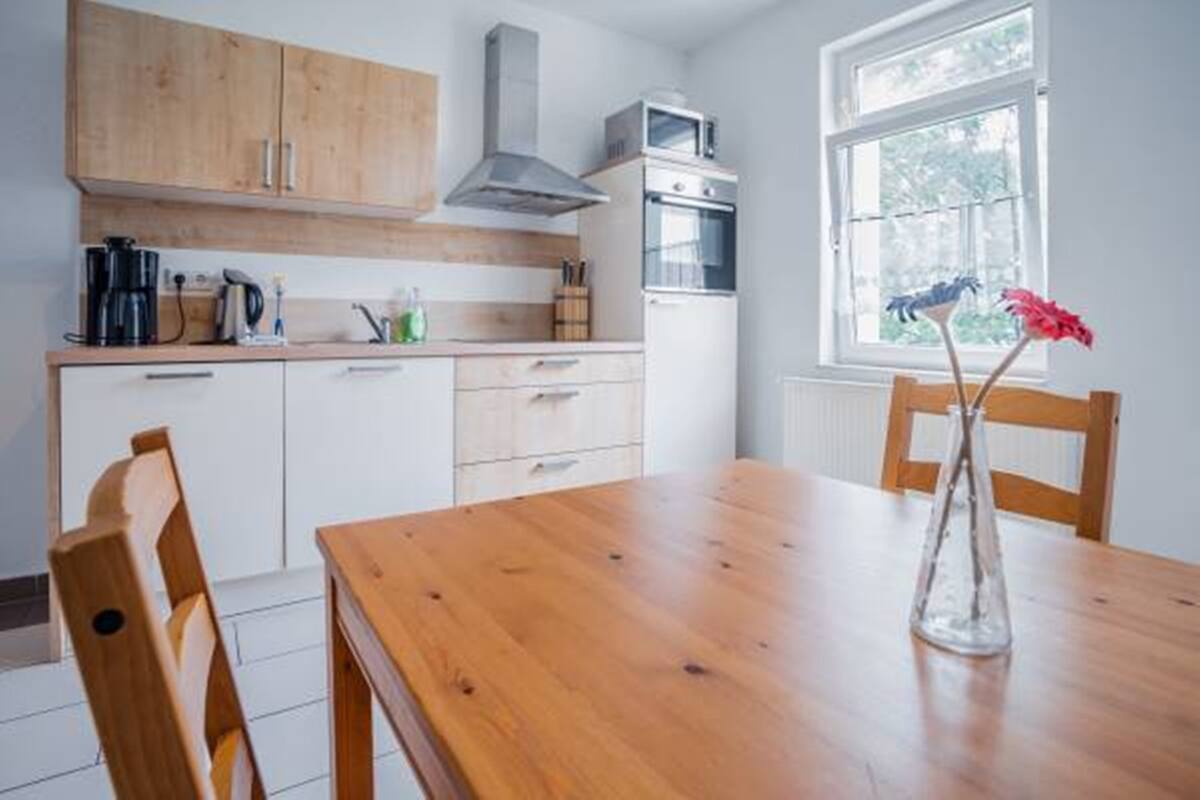 Une cuisine avec des meubles en bois, un fourneau et une fenêtre donnant sur un paysage verdoyant.