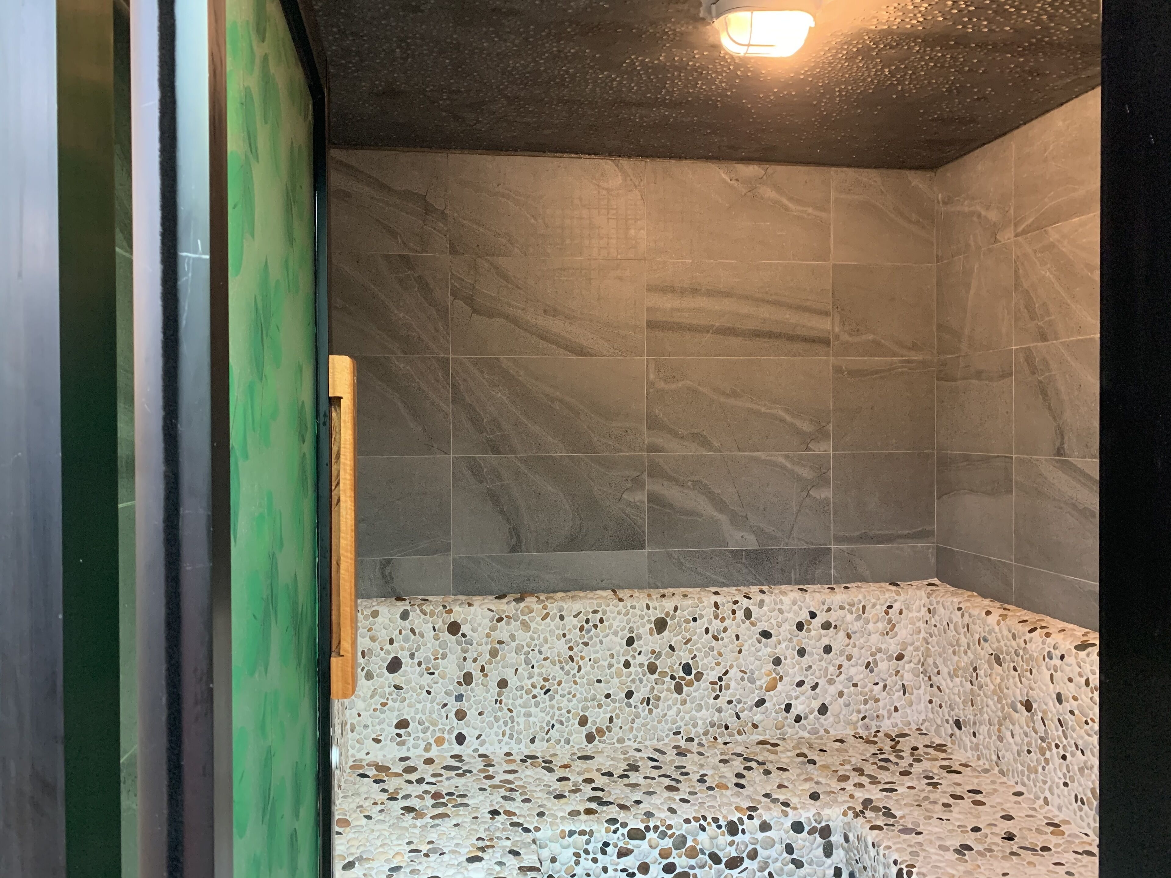 A spa room with a stone bench and a green wall.