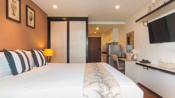 Habitación de hotel con cama, escritorio, silla, televisor y puerta que da a un baño.