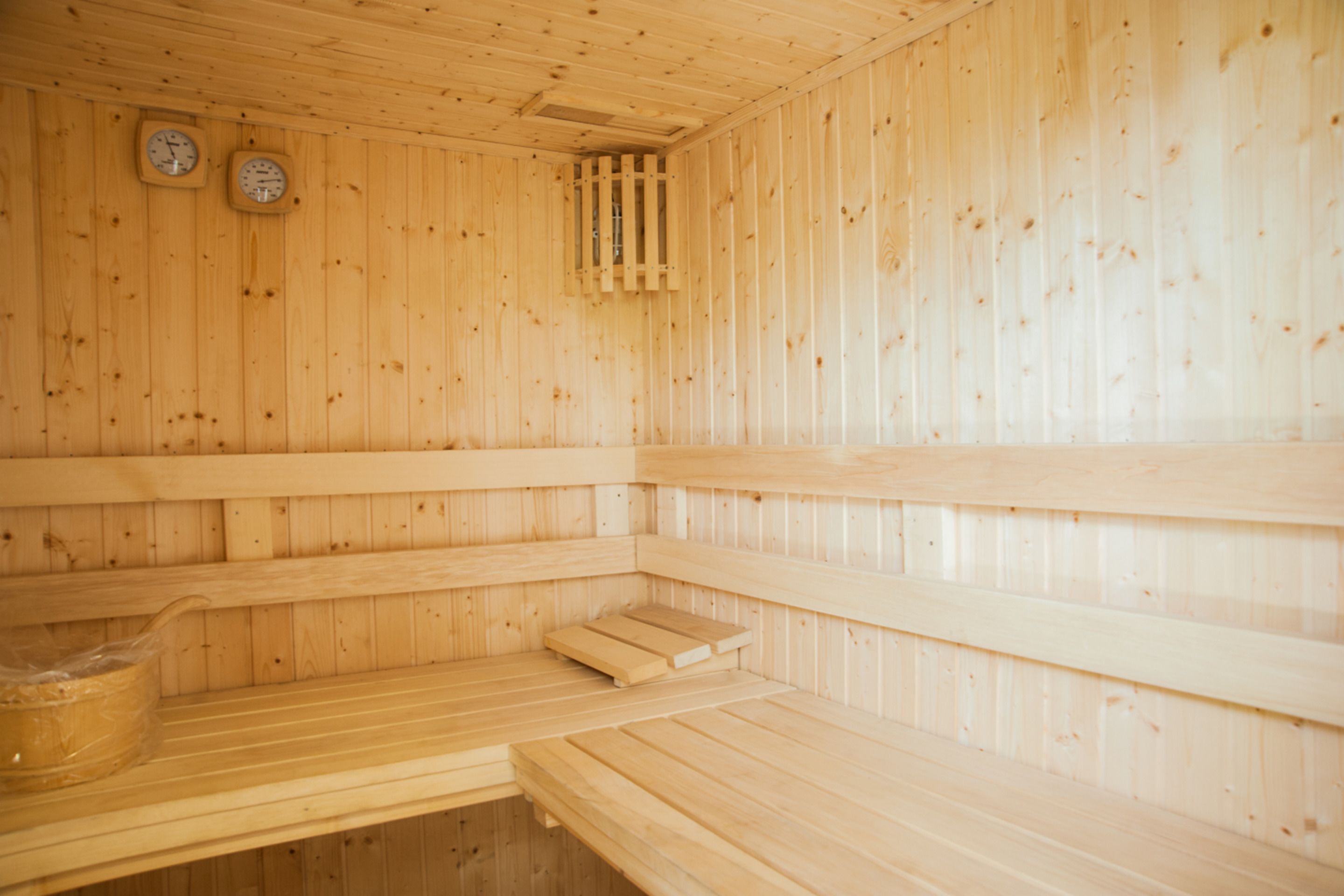 A sauna with wooden walls and benches, a clock, and a window.