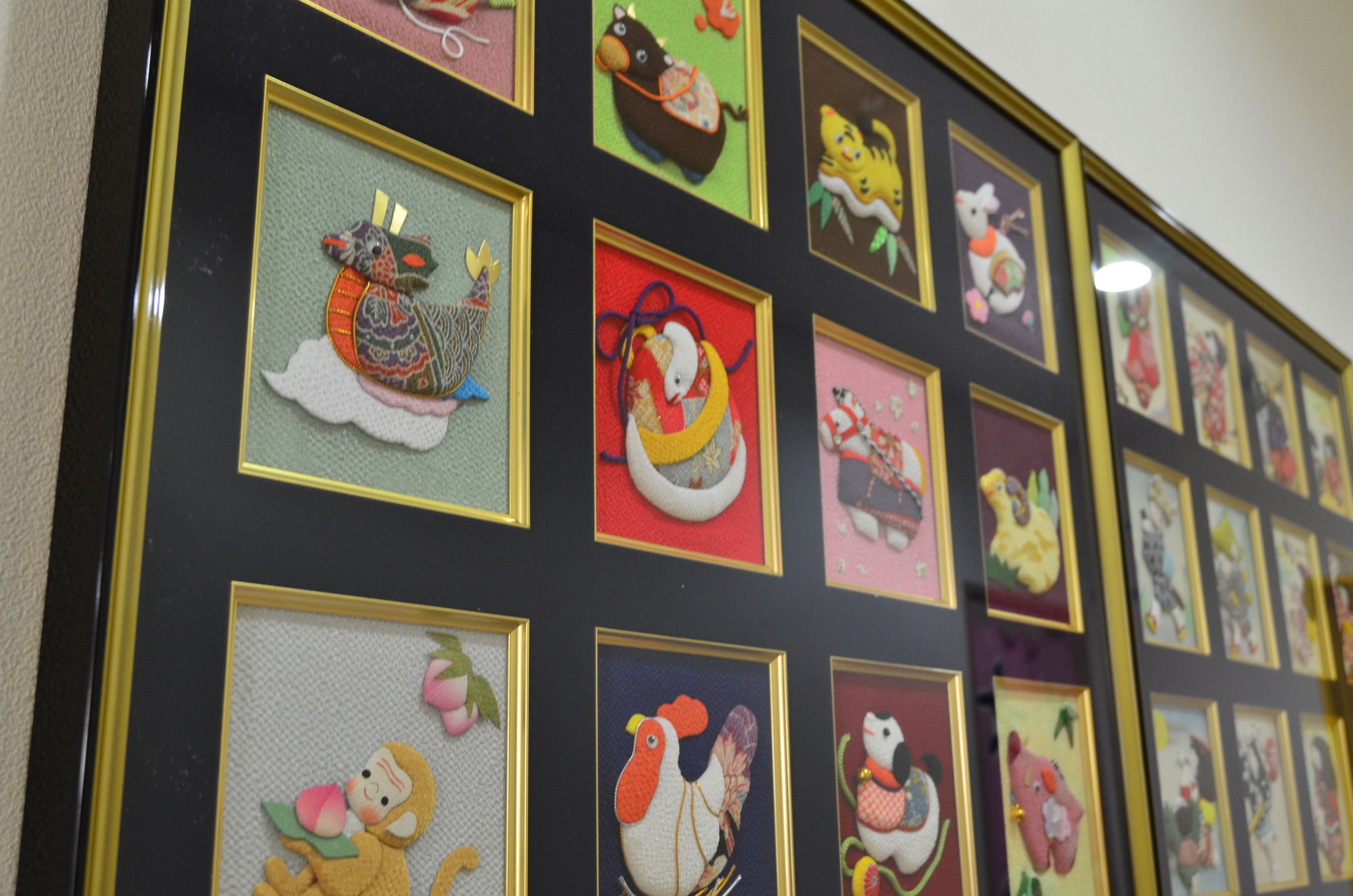 Eine Wand mit mehreren gerahmten Kunstwerken, die verschiedene Tiere und Designs zeigen.