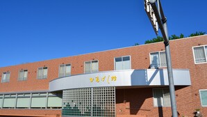 Un edificio con fachada curva, un amplio ventanal con diseño de cuadrícula y un letrero con caracteres japoneses.