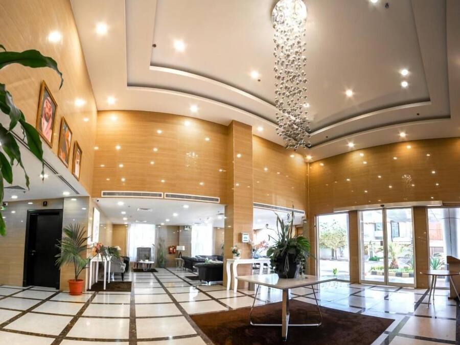 A spacious lobby with a high ceiling, recessed lighting, and a central chandelier.