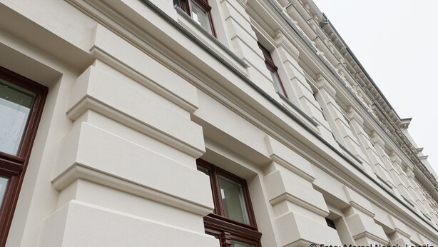 Un edificio de arquitectura clásica, con diseños de ventanas simétricas y molduras decorativas.
