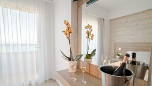 A modern hotel room with a wooden vanity, a large mirror, a champagne bottle, two glasses, and orchids. - Orpheus Studios (Kos)