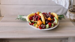 A fruit bowl on a table with a beige sofa and two wall art pieces in the background. - Orpheus Studios (Kos)