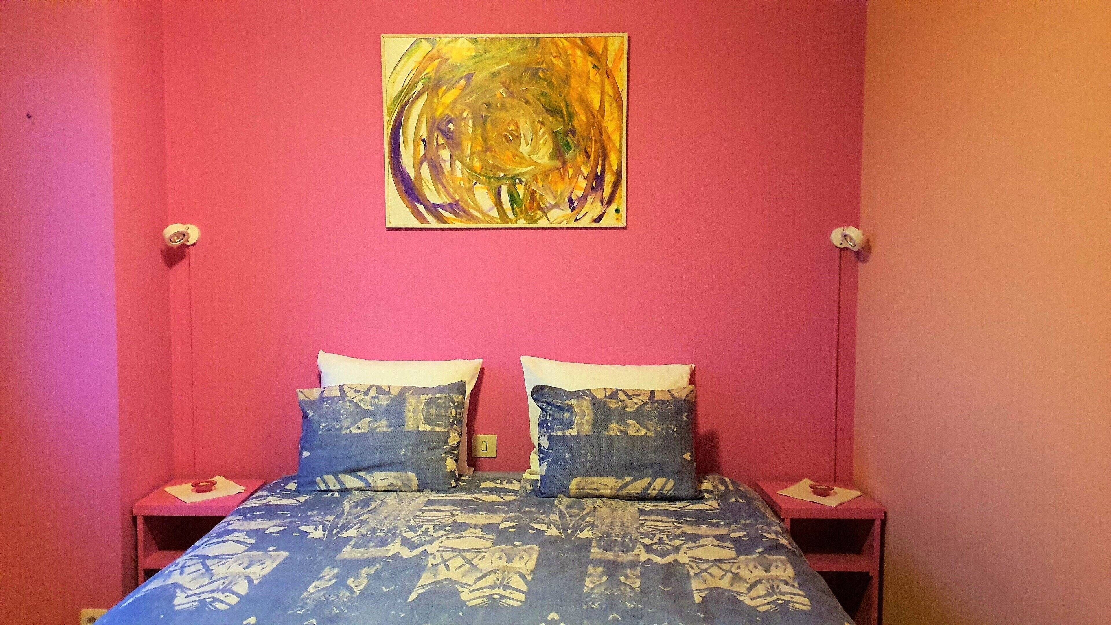 A room with a bed, two nightstands, and a wall-mounted painting.