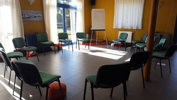 A room with multiple green chairs arranged in a semi-circle, a whiteboard with text, and a window with curtains.