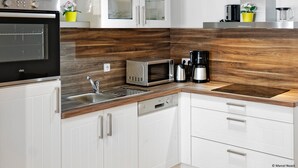Una cocina moderna con horno empotrado, microondas, cafetera y un lavabo.