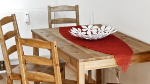 Una mesa de comedor de madera con cuatro sillas, un mantel rojo y un plato decorativo.