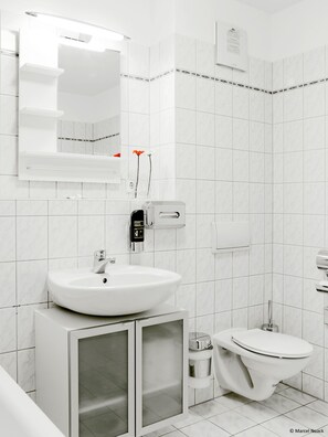 A modern bathroom with a white sink, mirror, and toilet.
