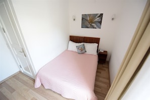 A bedroom with a bed, a nightstand, a wall-mounted lamp, and a door. - White Palace Otel (Adalar)