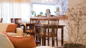 A cozy living room with a sofa, chairs, and a dining area with a coffee machine. - Nefeli Club (Lefkada)