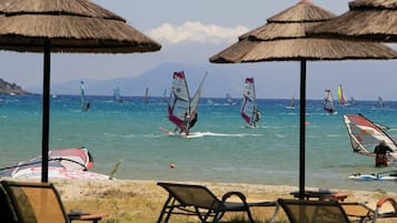 En la playa, camastros, sombrillas y windsurf