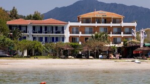 A beachfront hotel with multiple balconies, a sandy beach, and a mountain backdrop. - Nefeli Club (Lefkada)
