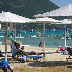位於海灘上、躺椅、遮陽傘、風浪板