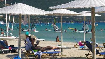 On the beach, sun loungers, beach umbrellas, windsurfing