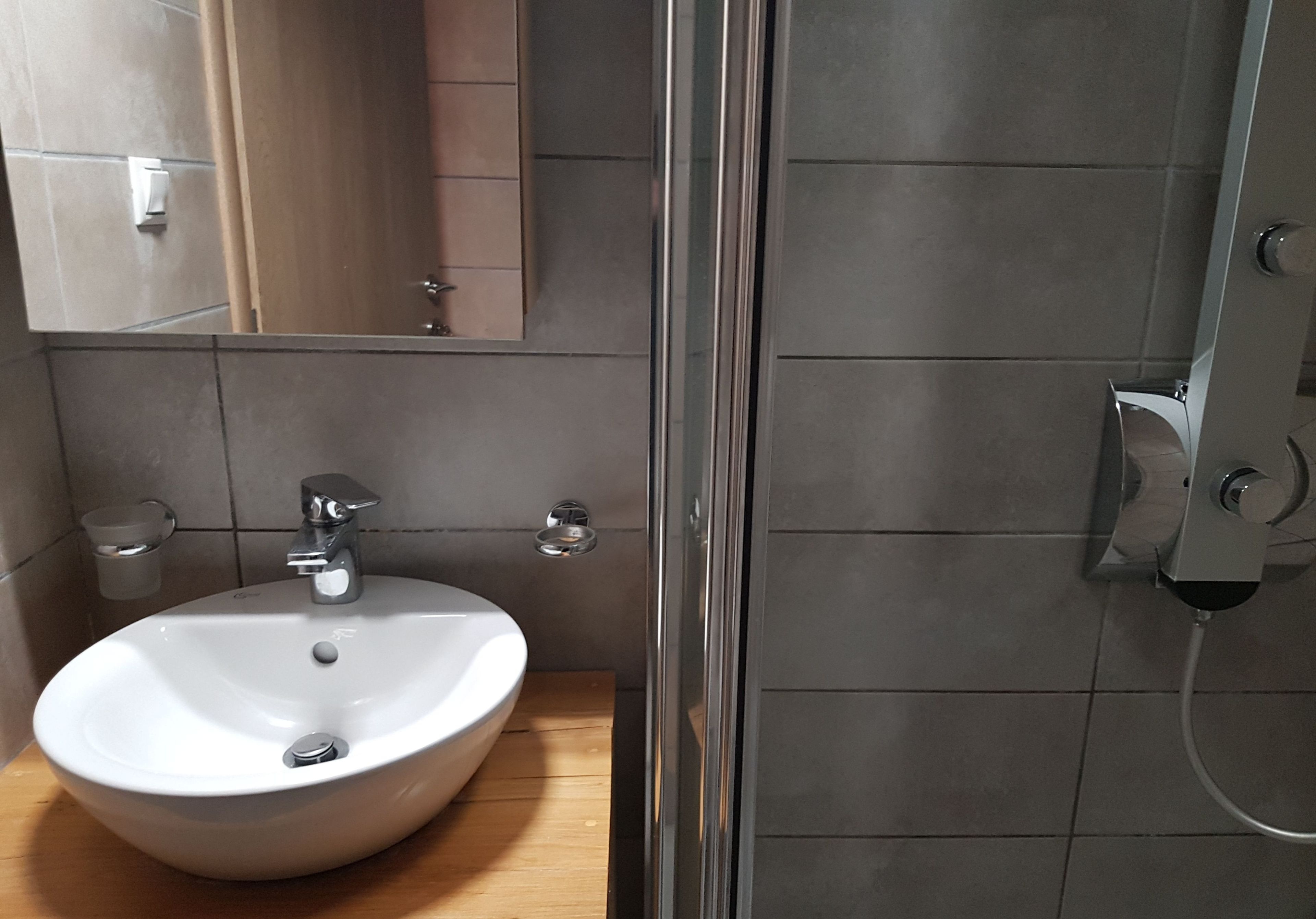A bathroom with a white sink, a mirror, and a shower area.