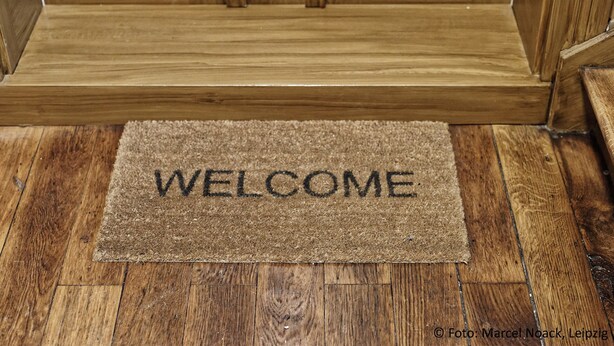 A wooden door with a welcome mat in front. - City Park Apartments Luther (Leipzig)