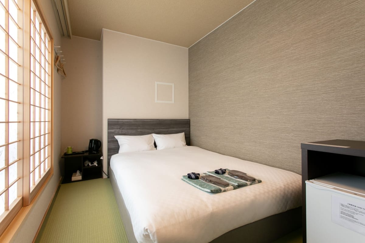 Habitación de hotel con cama, mesita de noche, escritorio y ventana con vistas.