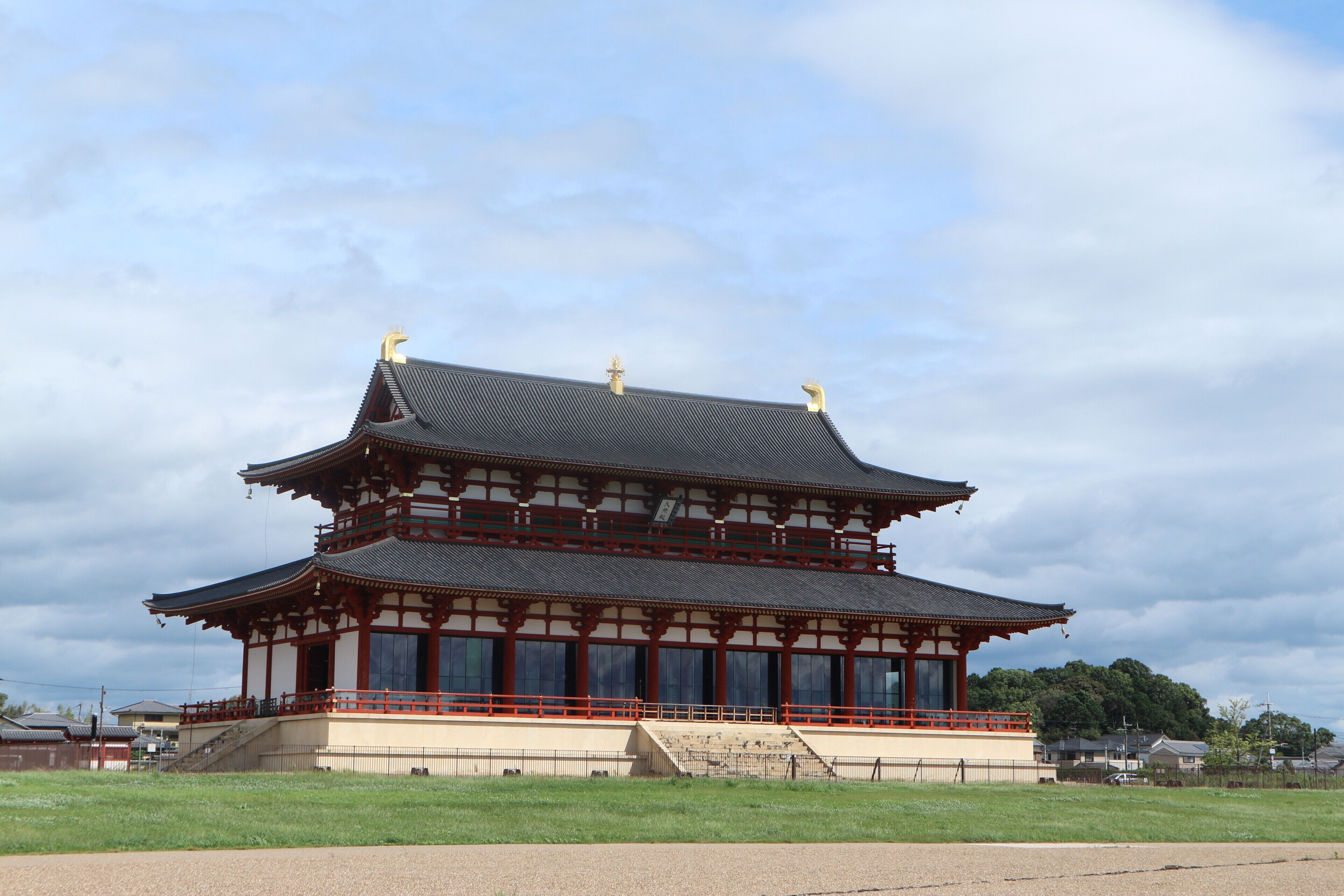 Un bâtiment traditionnel japonais doté d’un toit à plusieurs niveaux, d’une structure en bois et d’une cour entourée d’une clôture.