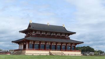 Un bâtiment traditionnel japonais doté d’un toit à plusieurs niveaux, d’une structure en bois et d’une cour entourée d’une clôture.