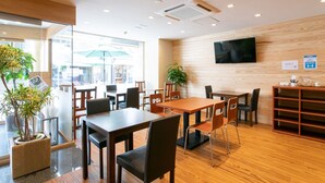 Un espacio interior moderno con suelo de madera, mesas y sillas dispuestas para comer o celebrar reuniones.