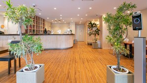 Un moderno vestíbulo de hotel con suelo de madera, una recepción y plantas en macetas.