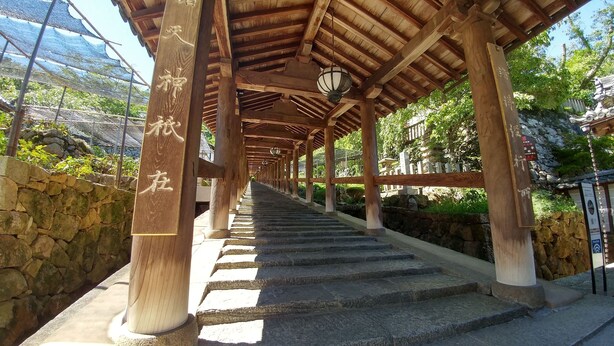 Una estructura de madera con escalones de piedra que conducen a un espacio cubierto con elementos arquitectónicos tradicionales asiáticos.