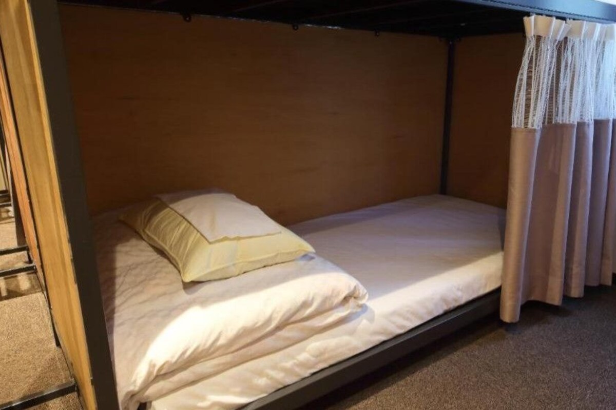 A single bed with a headboard, a pillow, and a curtain.