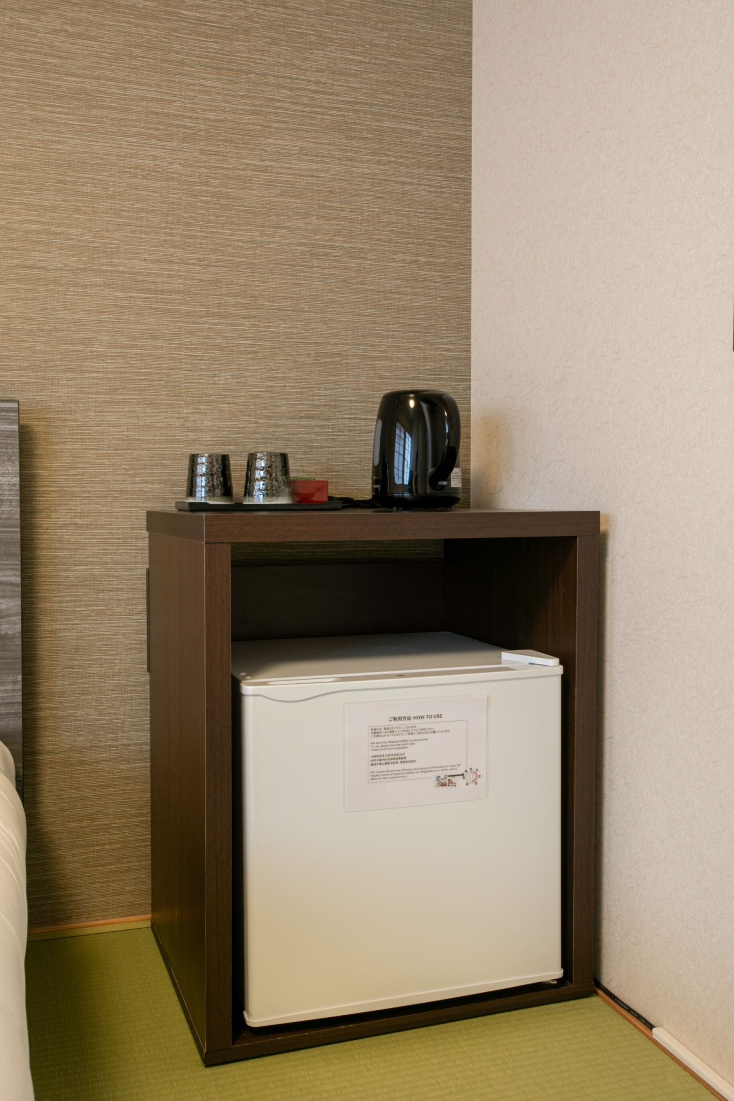 A compact minibar with a refrigerator, a coffee maker, and a tea kettle.