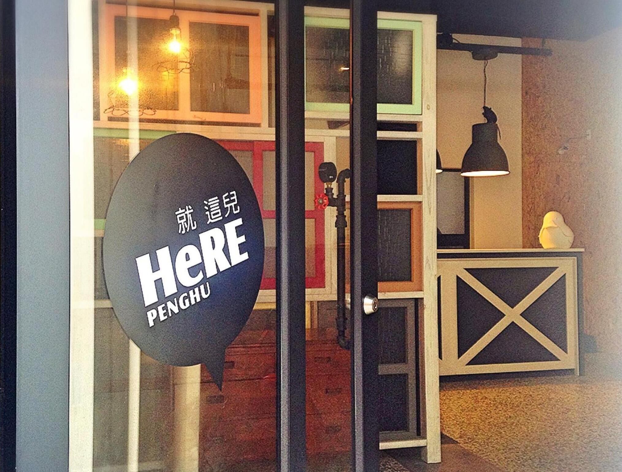 A restaurant entrance with a sign reading "HERE PENGHU".