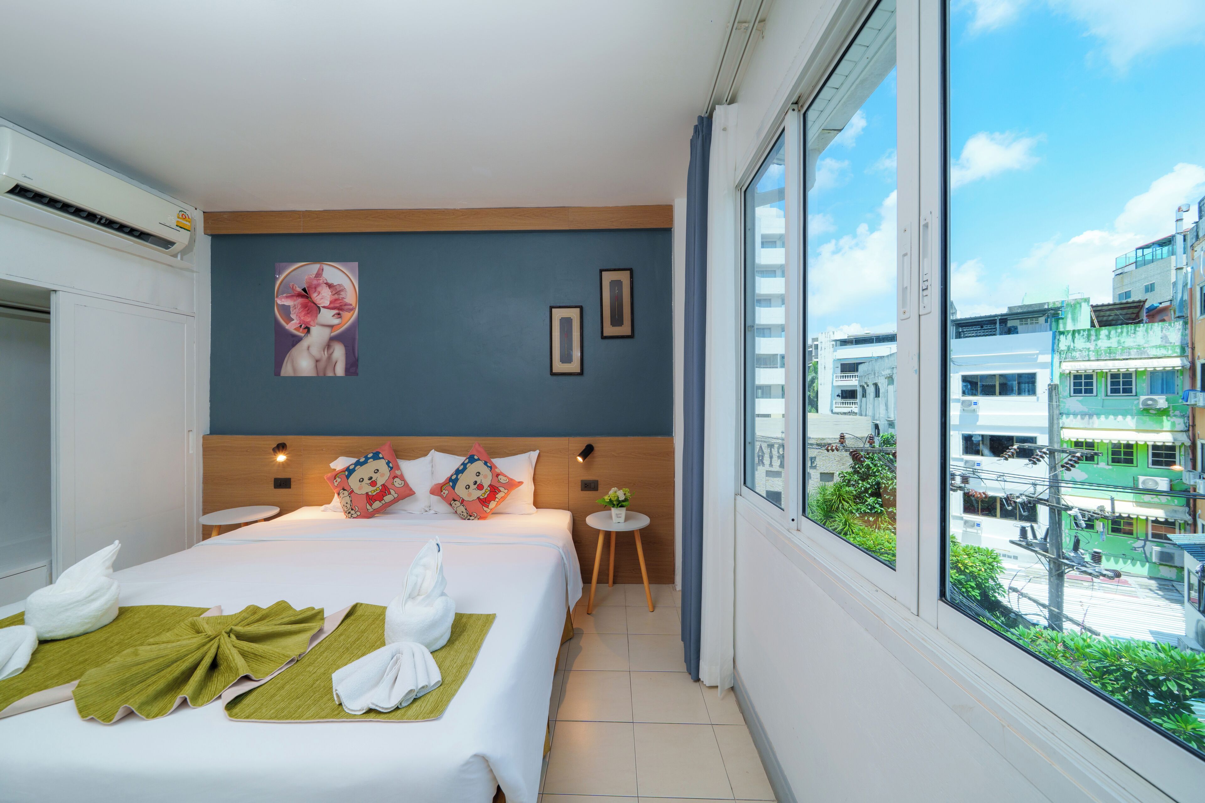 Habitación de hotel con una cama grande, vistas a la ciudad y una ventana con cortinas.
